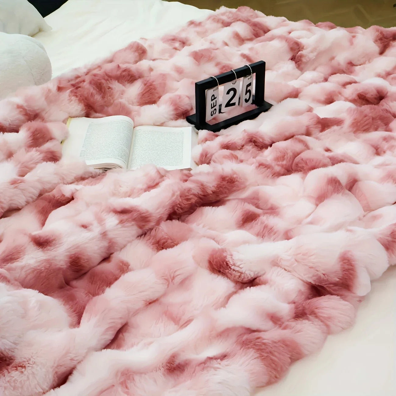 Pink fluffy blanket with a calendar and book on top