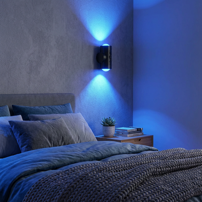 Bedroom with blue lighting from a wall sconce, featuring a bed and nightstand.