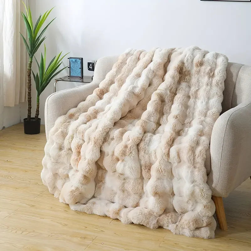 Fluffy beige blanket draped over a chair in a room with a plant and small table.