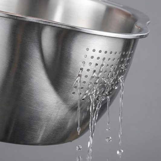 Metal colander with water dripping from it on a gray background